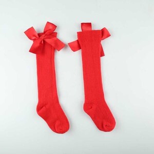 May include: A pair of red knee-high socks with a red satin bow at the top of each sock.