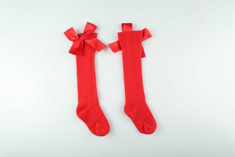 May include: A pair of red knee-high socks with a red satin bow at the top of each sock.