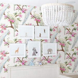 May include: A white crib with a white headboard and a white mattress. The crib is decorated with a white beaded chandelier and a wall with a white and pink floral pattern featuring peacocks. There are five framed animal prints above the crib.