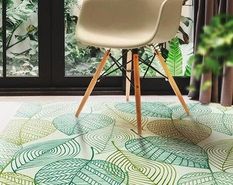 May include: A white chair with wooden legs sits on a green and white patterned rug with a leaf design. The rug is made of a soft, durable material and is perfect for adding a touch of nature to any room.