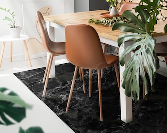 May include: Black and white marble patterned rug with a white table and brown chairs. The rug is placed in a dining room with a wooden wall behind the table.