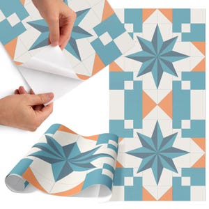 May include: Decorative peel-and-stick wallpaper with a geometric starburst pattern in shades of blue, orange, and white. The wallpaper is shown in a roll and being applied to a surface. The design is repeated across the surface.