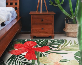 May include: A tropical-themed area rug with a white background and green palm leaves. A large red hibiscus flower is in the foreground, and a smaller yellow flower is in the background.