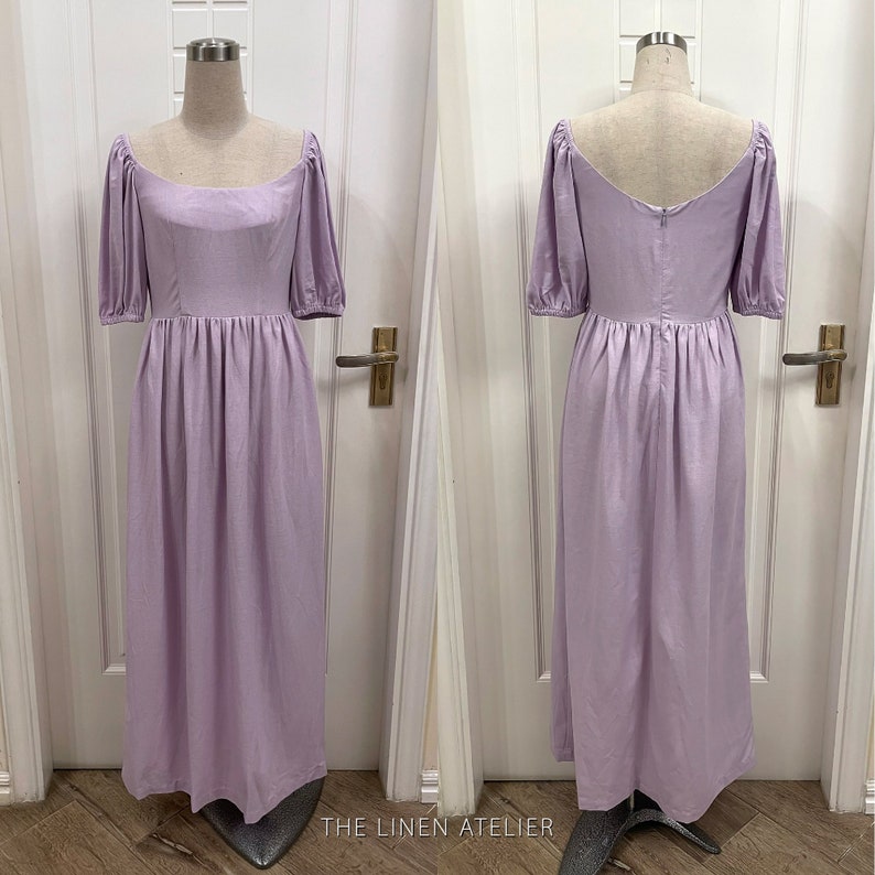 Puede incluir: Un vestido de lino lavanda con escote cuadrado y mangas abullonadas. El vestido tiene un corpi&ntilde;o ajustado y una falda fluida. El vestido se muestra en un maniqu&iacute; sobre un fondo blanco.