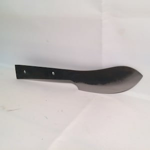 May include: A plain, unsharpened, black metal knife blade with two holes for a handle. The blade is curved and has a pointed tip.