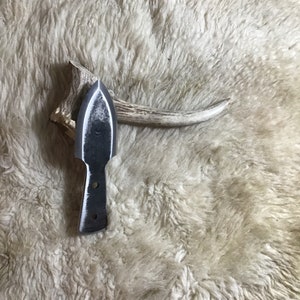 May include: A small, hand-forged knife with a pointed blade and a simple, rounded handle. The knife is made of steel and has a rustic, unfinished look.