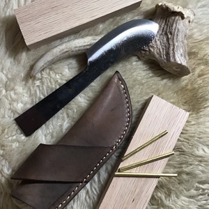 May include: A set of handmade tools for fire starting, including a knife with a leather sheath, a piece of antler, three brass rods, and two wooden blocks.