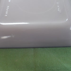 May include: A white rectangular baking dish with a light blue rim. The dish is made of ceramic and has a smooth, glossy finish.