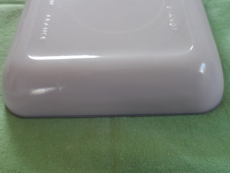 May include: A white rectangular baking dish with a light blue rim. The dish is made of ceramic and has a smooth, glossy finish.