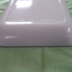 May include: White ceramic baking dish with a gray rim. The bottom of the dish has the words "Made in France" printed on it.