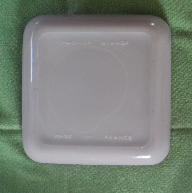 May include: White square ceramic dish with rounded edges. The bottom of the dish has the text "Made in France" and "Pyrex" logo.