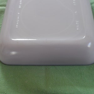 May include: White ceramic baking dish with a blue rim. The bottom of the dish has the words "Made in USA" printed on it.