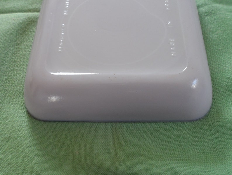 May include: White ceramic baking dish with a blue rim. The bottom of the dish has the words "Made in USA" printed on it.