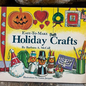 Puede incluir: Una portada de libro vintage titulada "Easy-To-Make Holiday Crafts" de Barbara A. McCall. La portada presenta ilustraciones de una calabaza, corazones, una corona y varias figuras artesanales con temática navideña. El libro es una guía para manualidades navideñas.