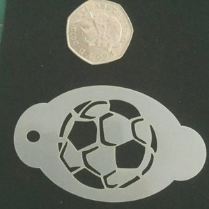 Könnte beinhalten: Eine weiße Plastik-Schablone eines Fußballs. Die Schablone ist etwa so groß wie eine 20-Cent-Münze.