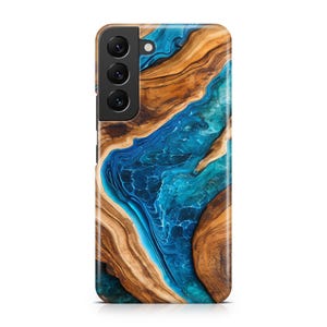 May include: A phone case with a wood grain and blue resin design. The case features a dark wood pattern with a flowing blue and turquoise resin river design. The phone case has a black camera module with three lenses.