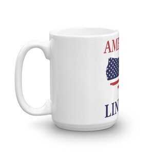 Puede incluir: Taza de caf&eacute; de cer&aacute;mica blanca con un dise&ntilde;o de bandera estadounidense roja y azul y el texto "America" y "Land of the Free" impreso en ella.