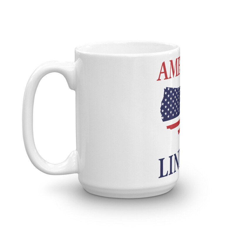 Puede incluir: Taza de caf&eacute; de cer&aacute;mica blanca con un dise&ntilde;o de bandera estadounidense roja y azul y el texto "America" y "Land of the Free" impreso en ella.