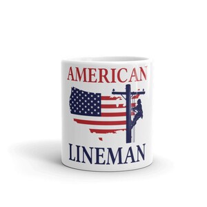 Puede incluir: Taza de cer&aacute;mica blanca con un dise&ntilde;o de bandera estadounidense roja, blanca y azul y el texto "AMERICAN LINEMAN".
