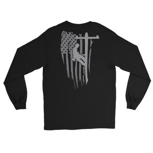 May include: Black long-sleeve t-shirt with a gray graphic of an American flag and a silhouette of a person working on a power line.