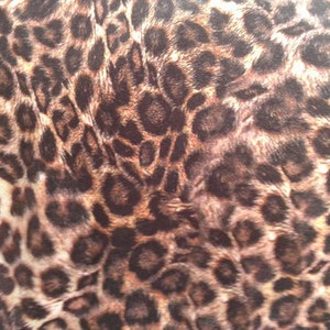 May include: A close-up of a brown and tan fabric with a leopard print pattern.