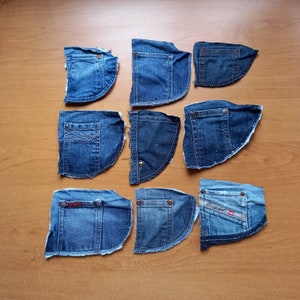 以下が含まれることがあります： 木製の表面に、さまざまな青色のデニムパッチが9つ並んでいます。パッチには、ステッチが施されているものと、生の端になっているものがあります。パッチはグリッドパターンで配置されています。