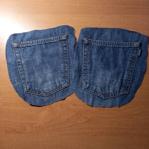 Puede incluir: Dos bolsillos de mezclilla azul cortados de un par de jeans. Los bolsillos est&aacute;n listos para ser cosidos en un nuevo proyecto.