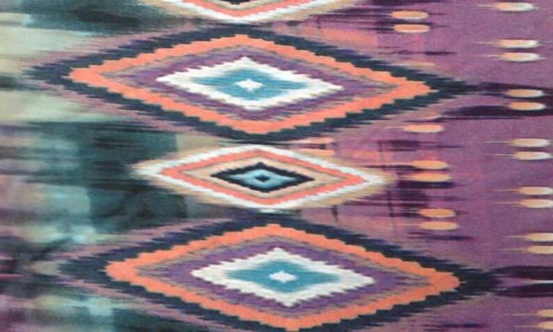 May include: A fabric with a repeating pattern of diamond shapes in shades of teal, purple, pink, and white. The diamonds are outlined in black and have a subtle ikat-like texture.