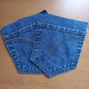Puede incluir: Dos piezas de tela vaquera azul con costuras contrastantes. La tela tiene un detalle de bolsillo con una costura curva.