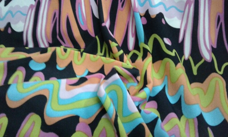 May include: Black fabric with a vibrant, abstract pattern. The design features flowing, wavy lines in shades of orange, pink, blue, and green against a black background. The fabric is gathered, showing its texture and drape.