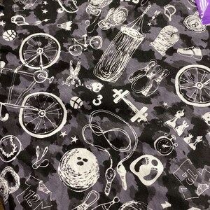以下が含まれることがあります： スケートボード、自転車、ボーリングピン、ボクシングバッグ、縄跳び、コンパス、ボウリングシューズなど、さまざまなスポーツやレジャーアクティビティが描かれた白黒のパターンファブリック。生地はカモフラージュ柄です。