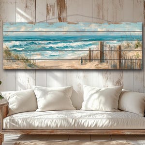 Puede incluir: Una pieza de arte mural rectangular de madera que representa una escena de playa. La obra de arte presenta un océano azul con olas blancas, una playa de arena y una valla de madera. El cielo es azul claro con nubes.