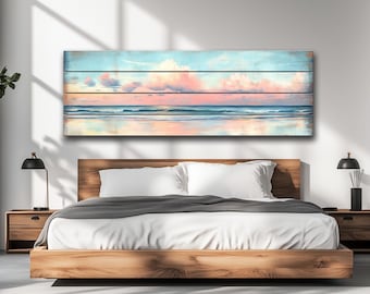 Puede incluir: Una obra de arte rectangular que representa una serena escena de playa. La obra presenta un cielo con nubes rosas y blancas sobre un océano en calma. La obra está montada sobre tablones de madera, creando una estética rústica.