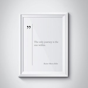 May include: A black and white framed print with a quote by Rainer Maria Rilke: "The only journey is the one within."
