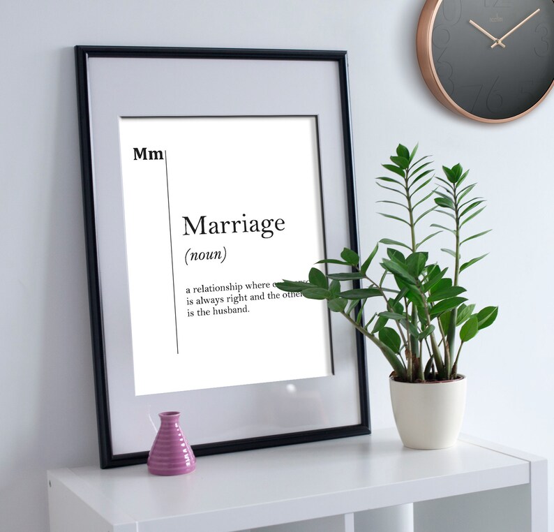 May include: A black framed print with a white background and black text that reads "Mm Marriage (noun) a relationship where one is always right and the other is the husband."