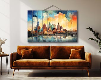 May include: A watercolour painting of a city skyline reflected in water. The artwork shows a colourful sky with blue, orange, and yellow tones. The buildings are in shades of brown, teal, and orange.