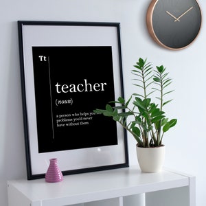 May include: Black and white framed print with the word "teacher" defined as "a person who helps you see problems you'd never have without them".