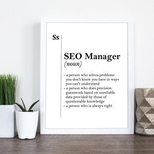 May include: A white framed print with a black and white definition of "SEO Manager". The definition reads: "a person who solves problems you don't know you have in ways you can't understand - a person who does precision guesswork based on unreliable data provided by those of questionable knowledge - a person who is always right"