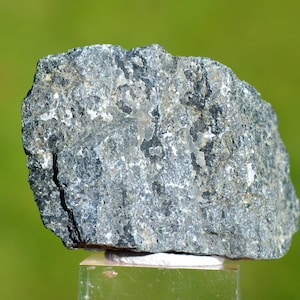 May include: A dark gray rock with a rough, textured surface. The rock has a slightly metallic sheen and is likely a type of igneous rock.