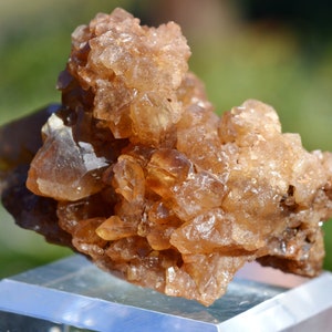 Könnte beinhalten: Ein Cluster aus braunen Calcitkristallen mit glasartigem, durchscheinendem Aussehen. Die Kristalle sind in einer natürlichen Formation zusammengefügt und bilden ein einzigartiges und interessantes Exemplar.