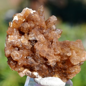 Könnte beinhalten: Ein Cluster aus braunen, durchscheinenden Quarzkristallen mit einer rauen, strukturierten Oberfläche. Die Kristalle sind in einem zufälligen, organischen Muster zusammengefügt.