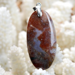 May include: A brown, white, and gray agate pendant with a silver bail. The pendant is oval shaped and has a natural, organic pattern.
