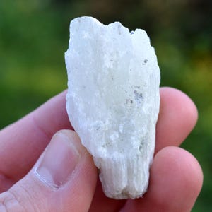 Könnte beinhalten: Ein weißer Selenitkristall mit faseriger Textur. Der Kristall ist etwa 7,5 cm hoch und hat eine natürliche, raue Form.