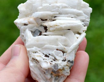May include: A white barite cluster with a layered, stacked formation. The cluster has a rough, natural texture and is accented with small, clear quartz crystals.