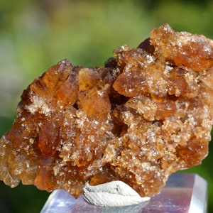 Könnte beinhalten: Ein Cluster aus braunen Calcitkristallen mit einer rauen, strukturierten Oberfläche. Die Kristalle sind durchscheinend und haben einen leichten goldenen Farbton.