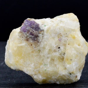 May include: A cluster of white, translucent crystals with a purple crystal embedded in the centre.