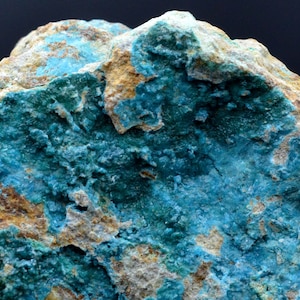 May include: A close-up of a rough, textured rock with patches of blue-green and brown. The rock has a natural, earthy appearance.