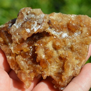 Könnte beinhalten: Ein Cluster aus braunen und orangefarbenen Calcitkristallen mit einer rauen, strukturierten Oberfläche.