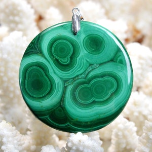 May include: A round green malachite pendant with a silver bail. The malachite has a swirling pattern of green and white.