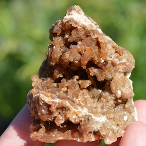 Könnte beinhalten: Ein Cluster aus braunen und weißen Calcitkristallen in einer rauen, natürlichen Formation. Die Kristalle sind in einer dichten, unregelmäßigen Form zusammengefügt.